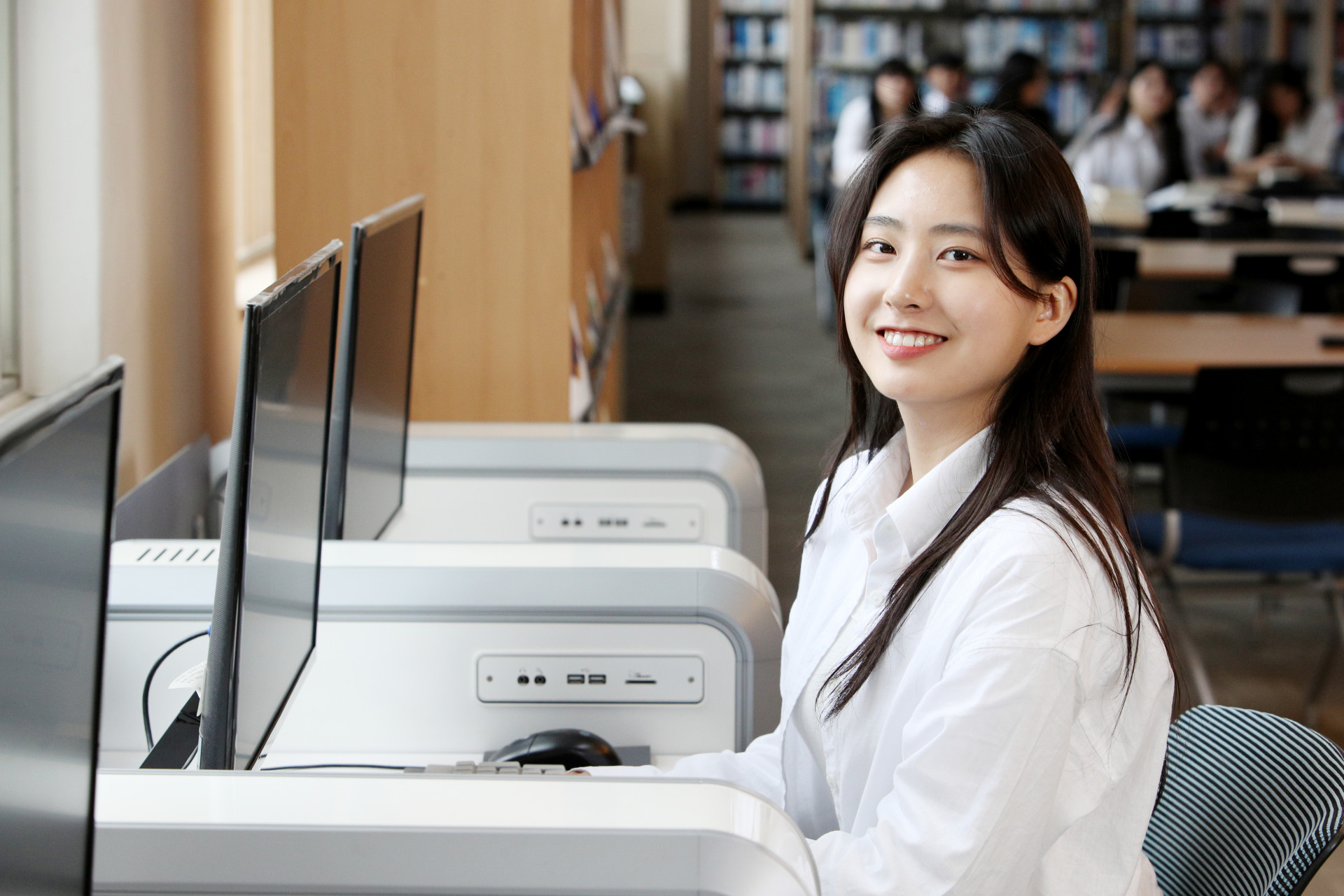 도서관 검색 컴퓨터 앞에 앉아있는 학생의 사진