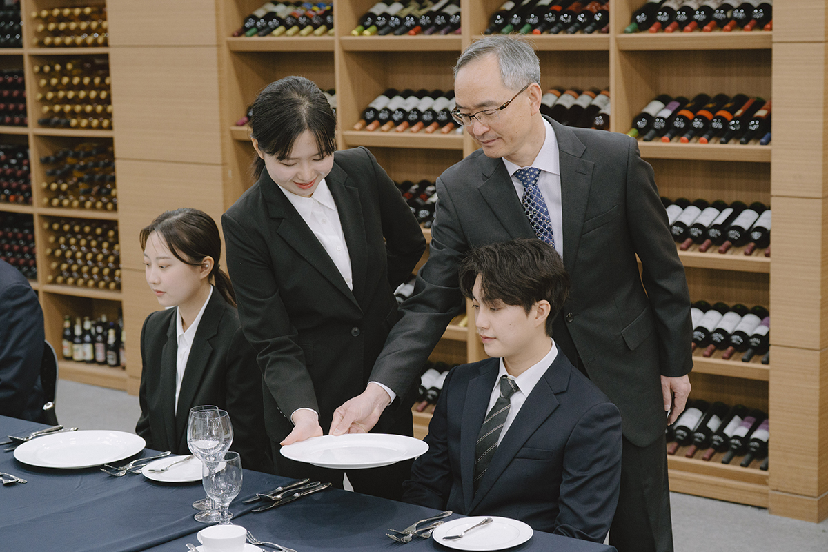 호텔에서 접시 서빙하는 방법을 교육받는 학생들의 사진