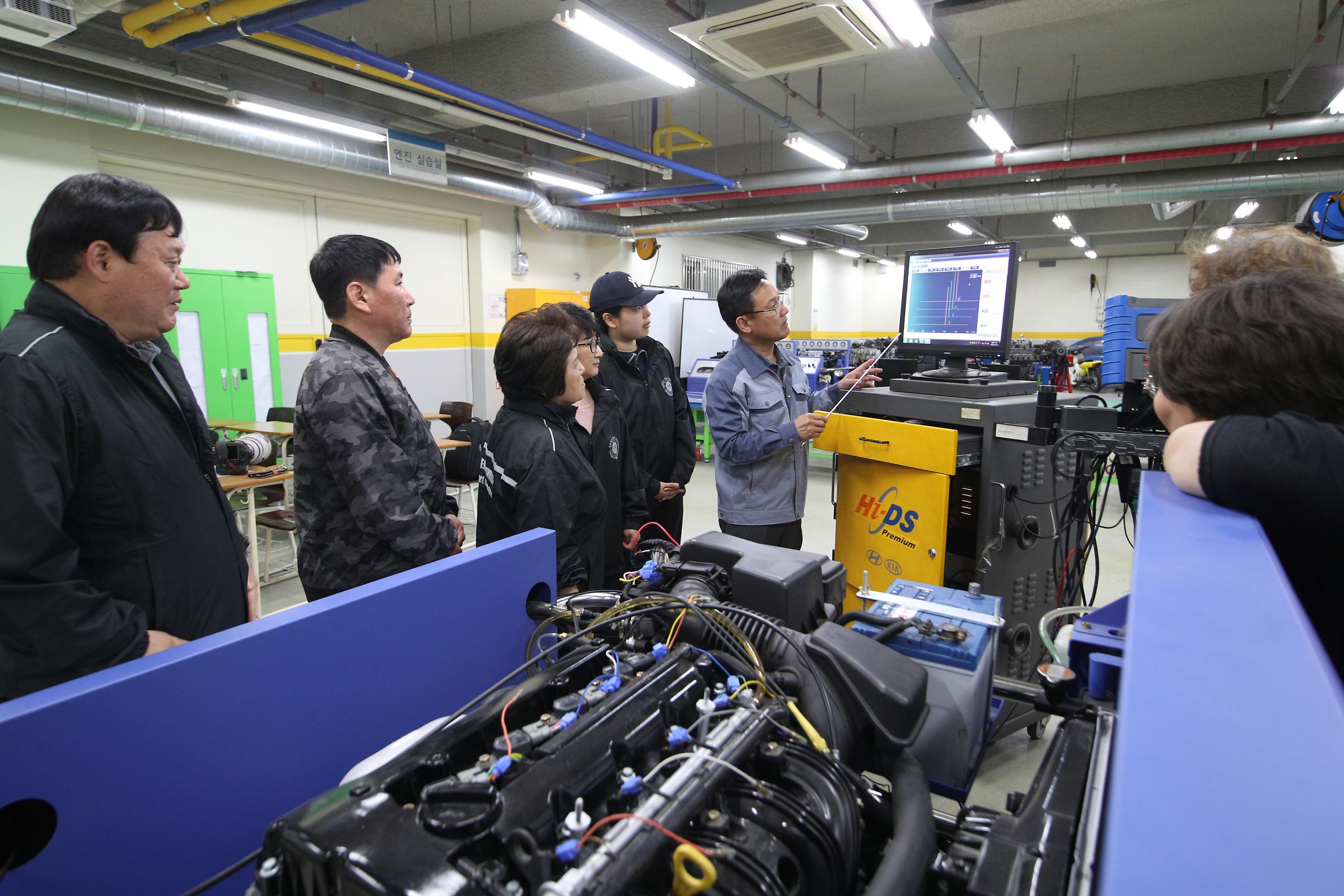 자동치와 연결 된 컴퓨터 앞에서 설명하는 교수님과 경청하는 학생들(다른 각도의 사진)