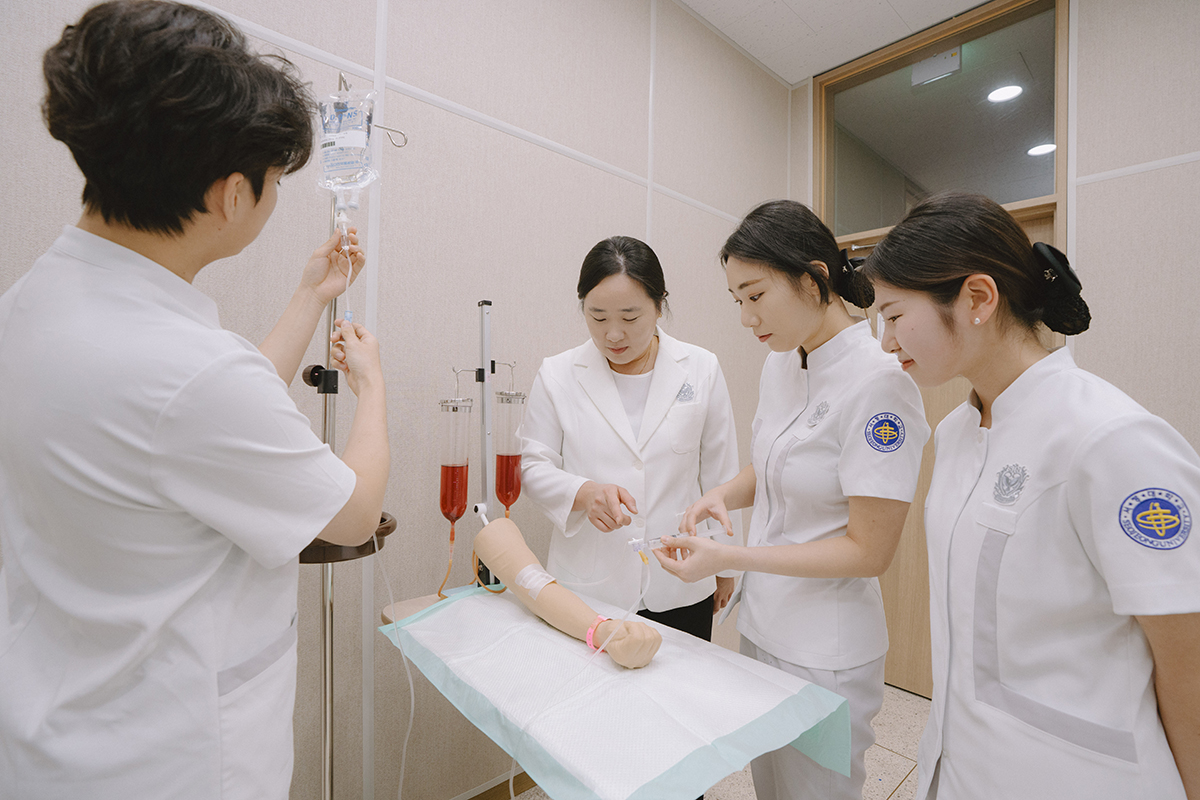 팔 마네킹에 주사 실습을 하고 있는 학생들