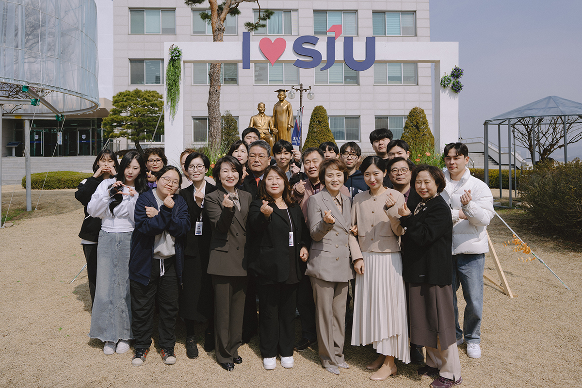 학교 동상 앞에서 단체사진을 찍고 있다.